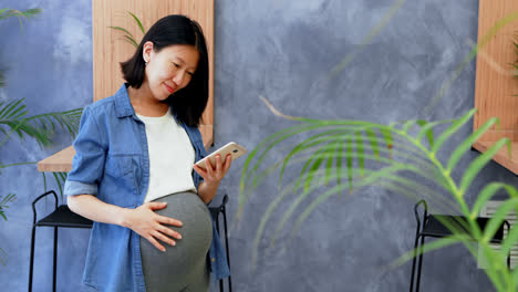 pregnant woman using mobile phone in office 4k