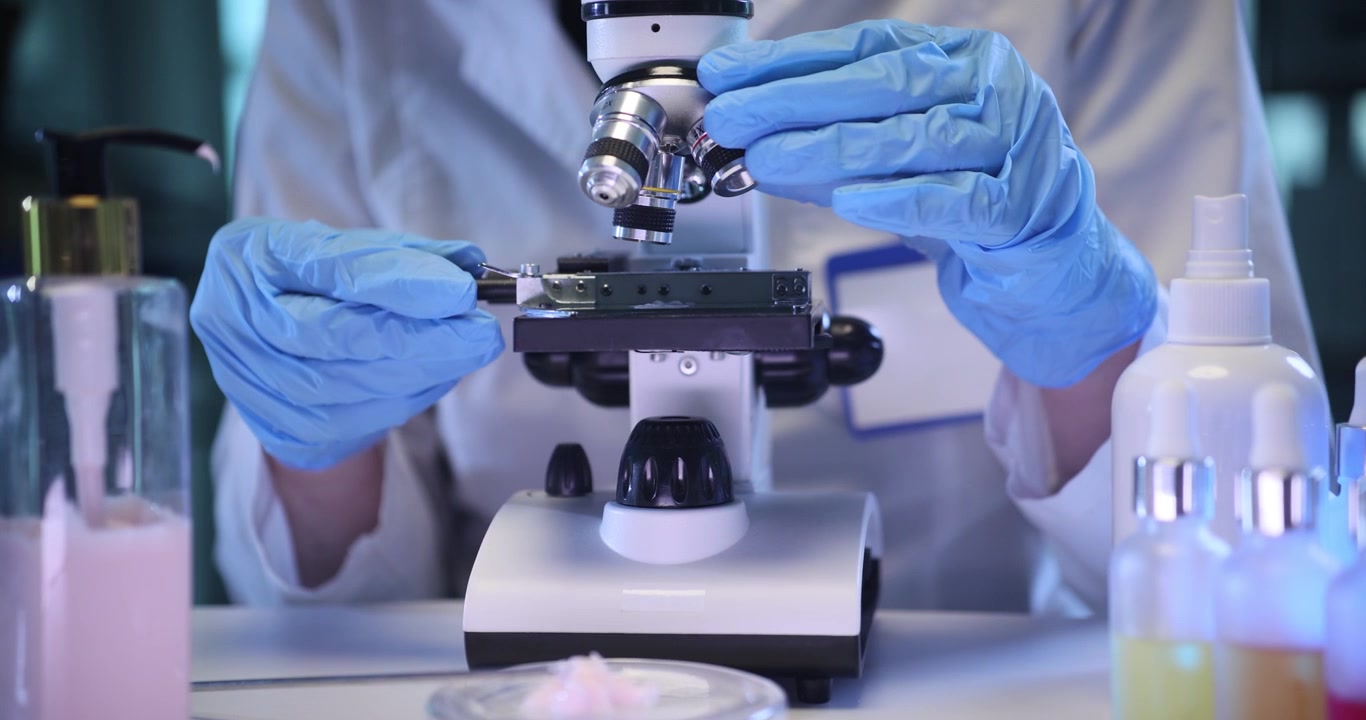 Doctor looks at cream specimen in microscope on lab desk