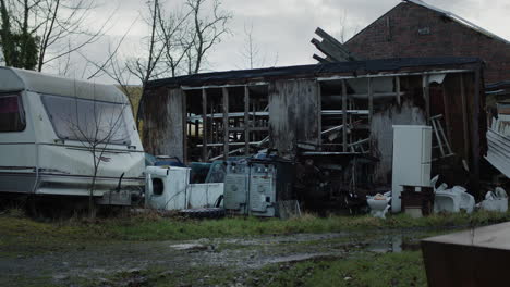 abandoned house with caravan and trash outside