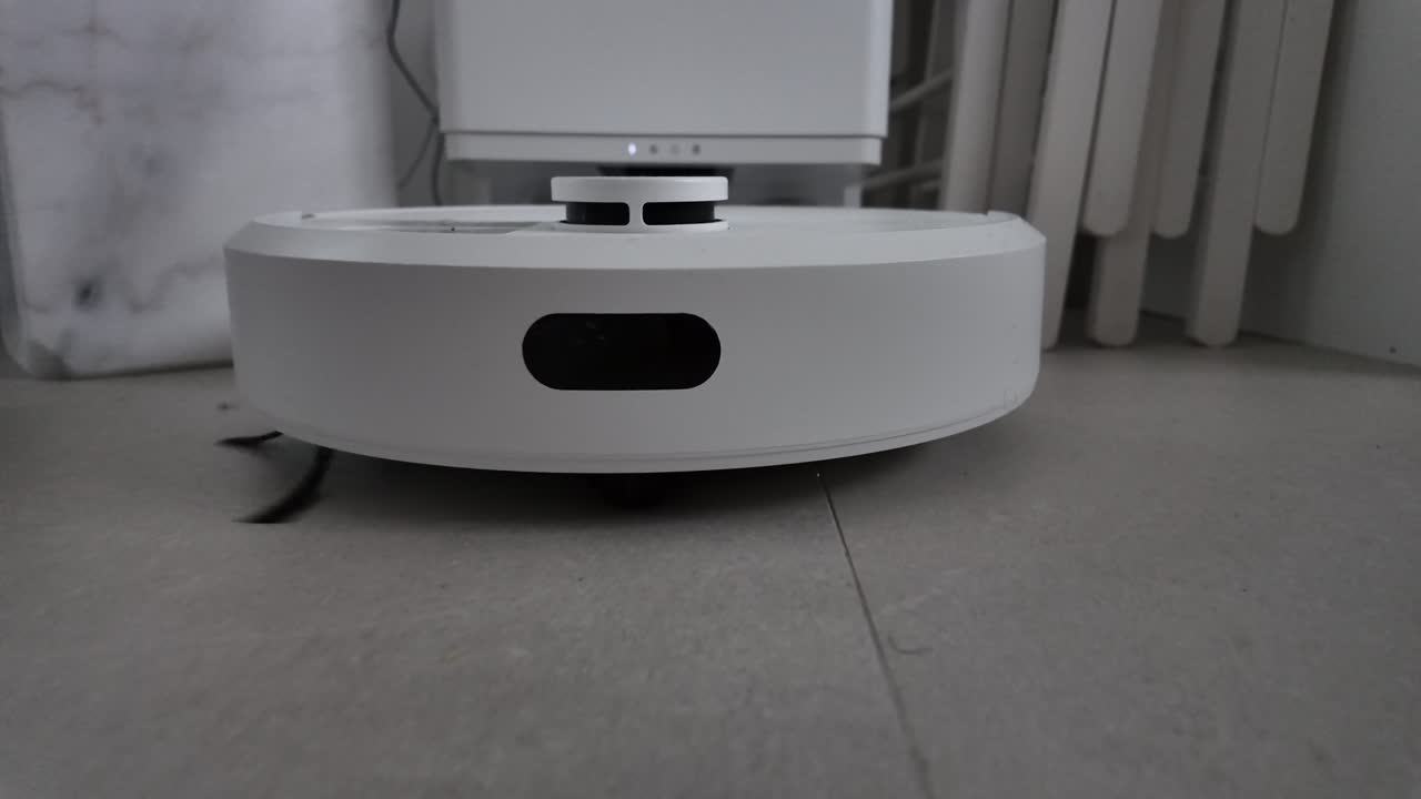 Robotic floor cleaner gliding across a tiled indoor surface at low angle