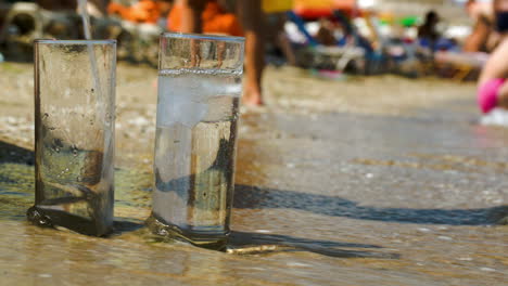 pouring water into two glasses on beach