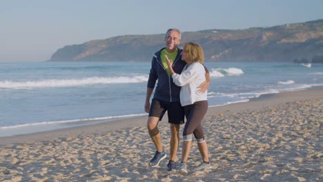 Feliz-Pareja-De-Ancianos-Abrazándose-Y-Caminando-Por-La-Costa-Del-Océano