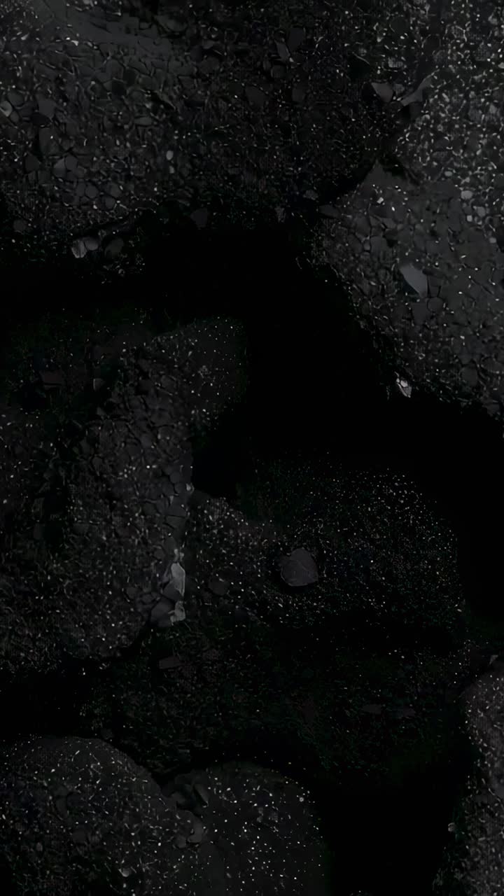 Pystyvideo: Panoroiva kamera näyttää pikkukivipintaa, jossa on kiviä ja keskellä oleva kuoppa hämärtyvällä rannalla
