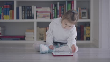 바닥에 태블릿을 가진 어린 소녀