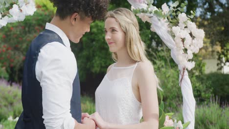 happy diverse couple holding hands on sunny day at wedding