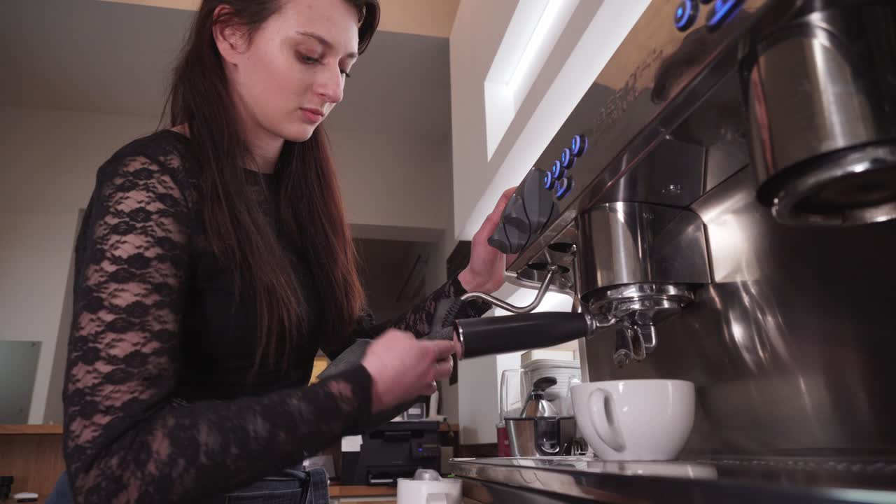 barista femenina haciendo café con leche o capuchino, vertiendo crema de leche en una taza, primer plano de ángulo bajo