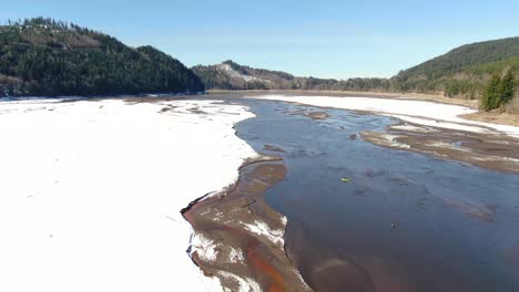 Volando-Sobre-El-Lago-Alder-En-Un-Soleado-Día-De-Invierno-Con-El-Suelo-Cubierto-De-Nieve