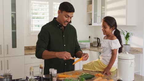 Hispanic-father-teaching-daughter-sitting-on-countertop-cooking