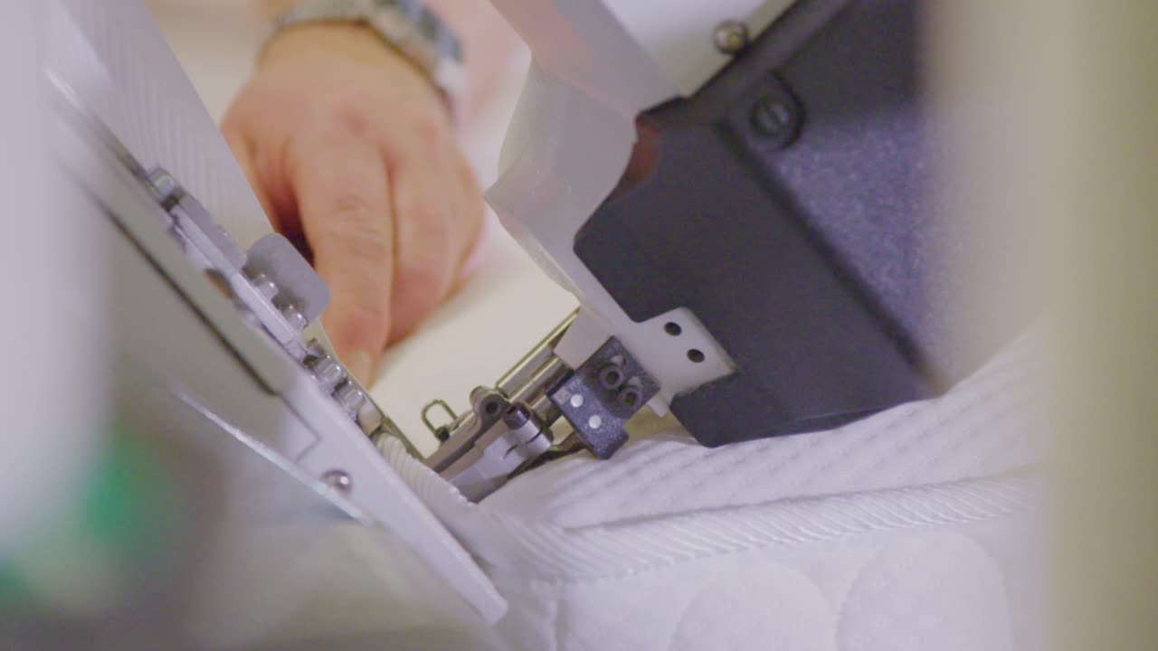 밝은 공장 환경에서 정밀 기계로 박스 스프링 침대를 만드는 손