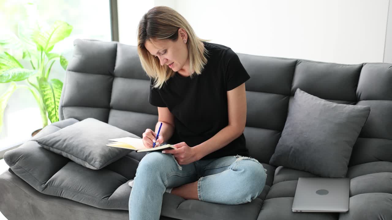Donna che scrive su un quaderno sul divano