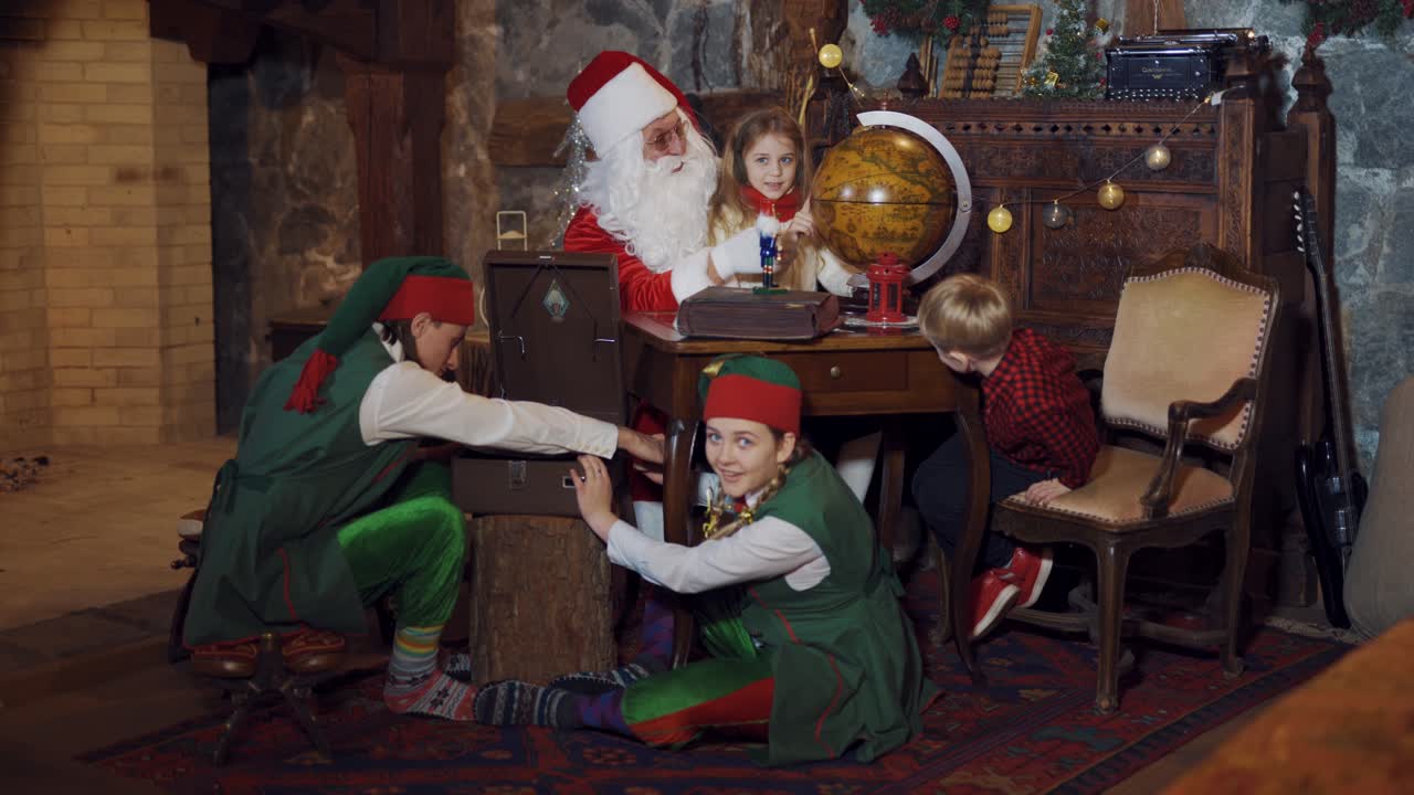 Santa Claus showing countries on the globe to little kids. Fairy elves trying to make music on old recorder in Santa's residence. Christmas time.