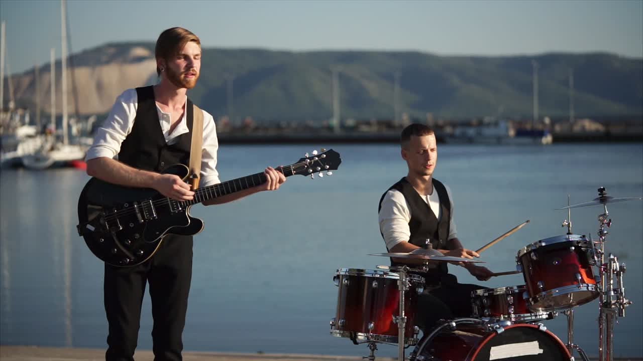 Two musicians performing live by the harbor
