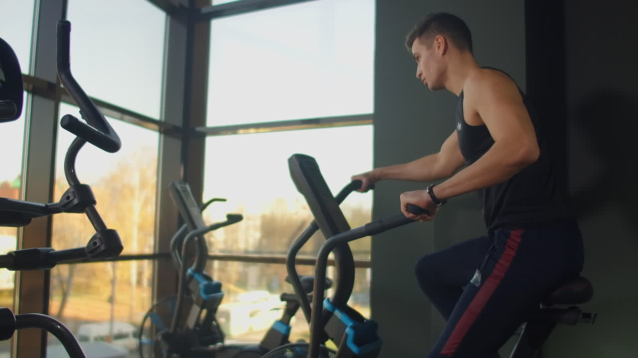 Young active men spinning a air bike in gym with trainers. male training on air bike.