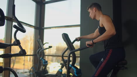 young active men spinning a air bike in gym with trainers. male training on air bike.