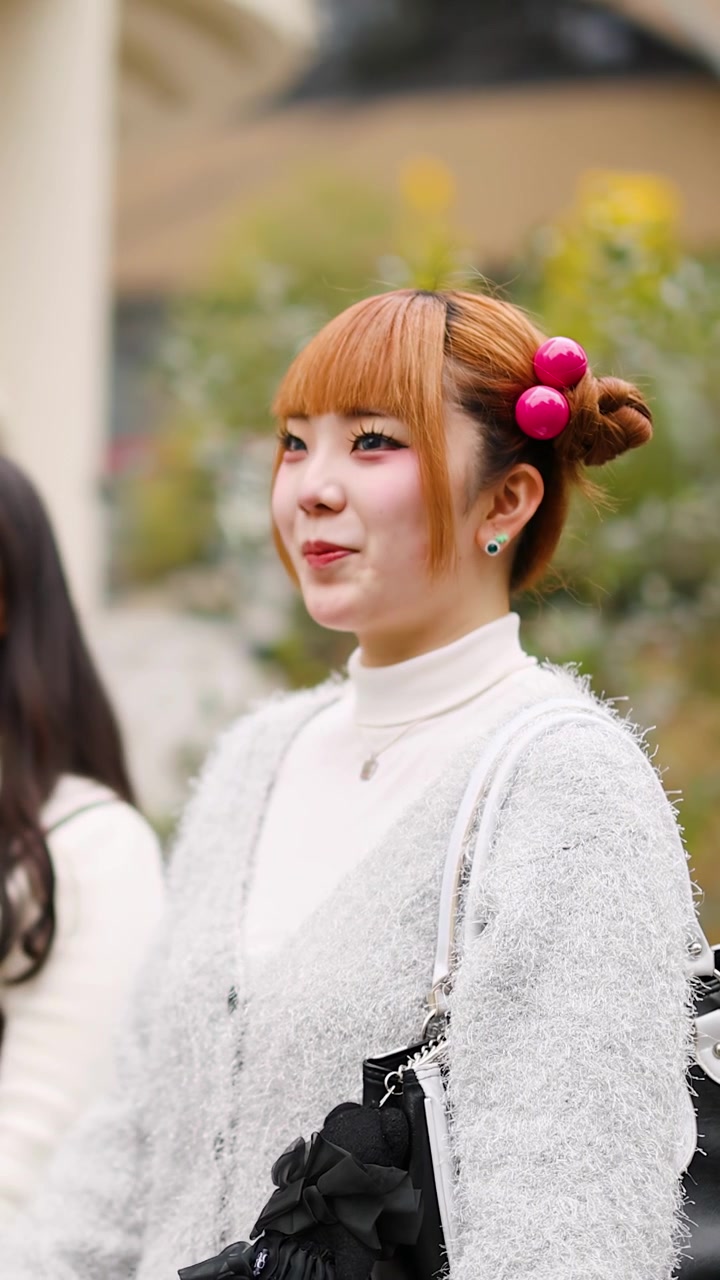 Una donna giapponese elegante parla e sorride all'aperto ad Harajuku, Tokyo, indossando un'originale moda di strada