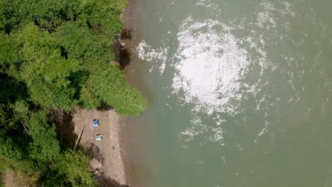 Backpackers-walking-on-riverbank,-Yuli-town-in-Yangshuo-China,-aerial-view