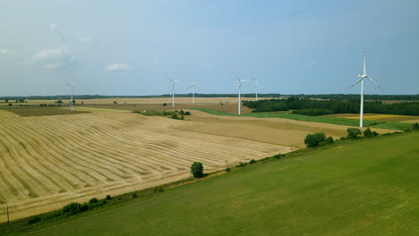 Grandes-Aerogeneradores-Con-Palas-En-El-Campo-Sobre-El-Cielo-Azul,-Parque-Eólico-En-Cámara-Lenta-Drone-En-Movimiento-Recto