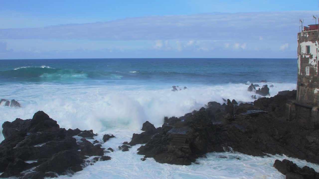 una gran ola del océano atlántico se rompe en una costa rocosa en un día soleado durante una tormenta en puerto de la cruz en las canarias , tiro de mano de gran angular