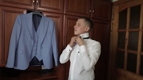 groom getting ready for his wedding day in a blue suit and bowtie