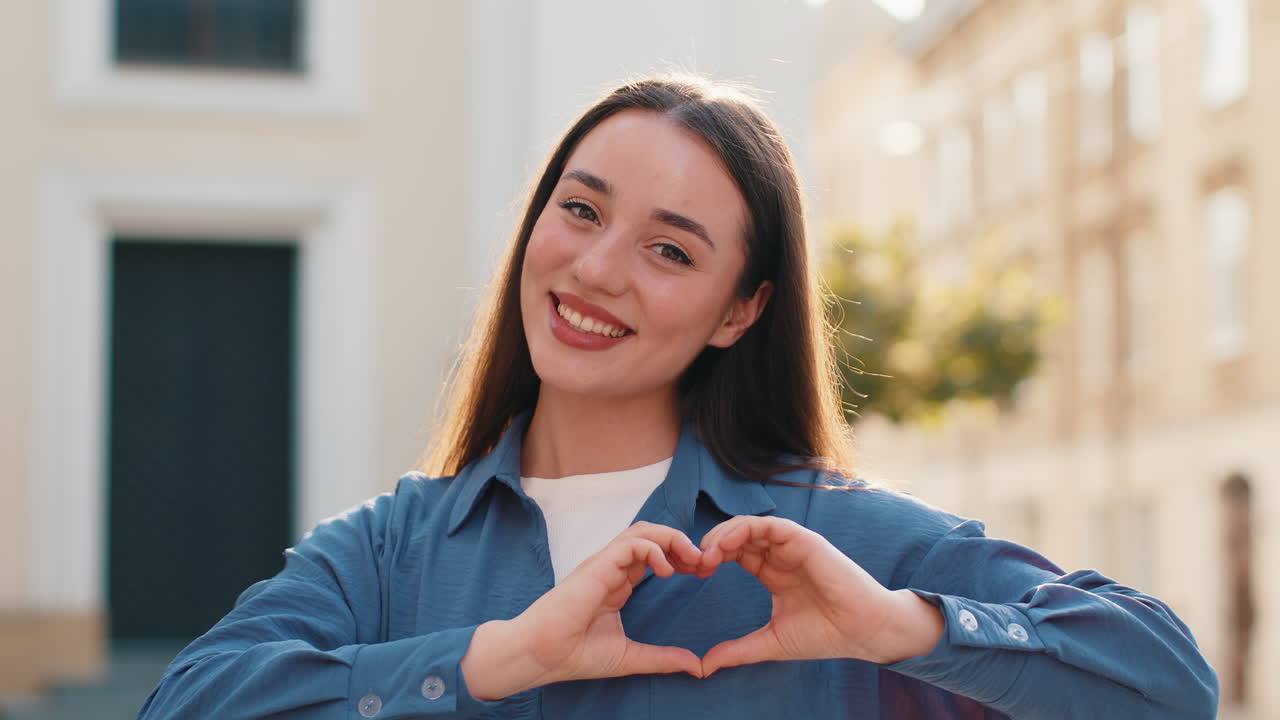 Pretty woman makes symbol of love showing heart sign to camera express romantic positive feelings