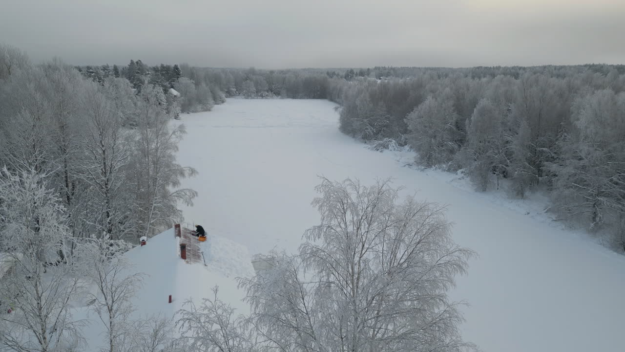 멀리 떨어진 부지에 눈으로 인 지붕을 고치고 있는 사람, 공중 사진