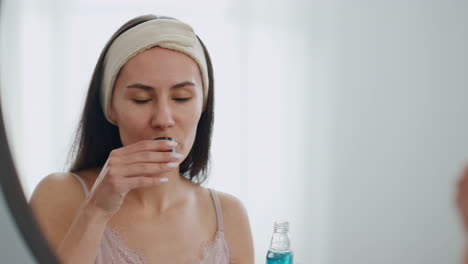 happy model pouring mouthwash at bathroom close up. smiling lady rinsing mouth