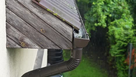 close-up of rainwater flowing from a roof gutter during a storm