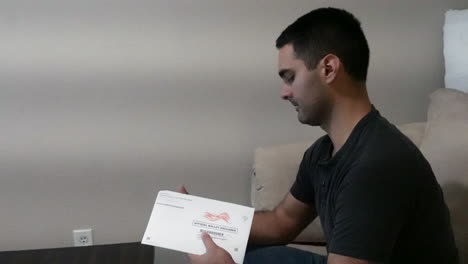 el joven abre y lee la boleta electoral oficial por correo en el sofá en casa