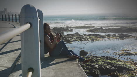 animation of smiling biracial woman taking photo with camera on promenade