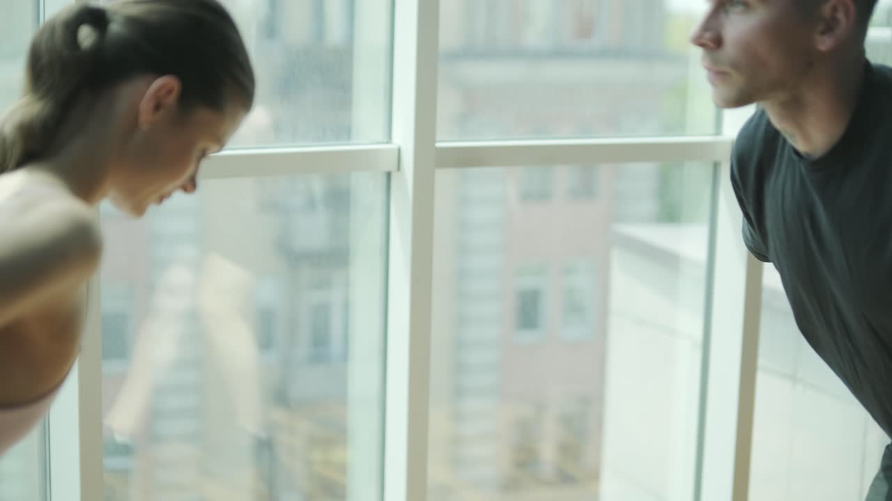 Woman practicing ballet in studio and man in urban casual style