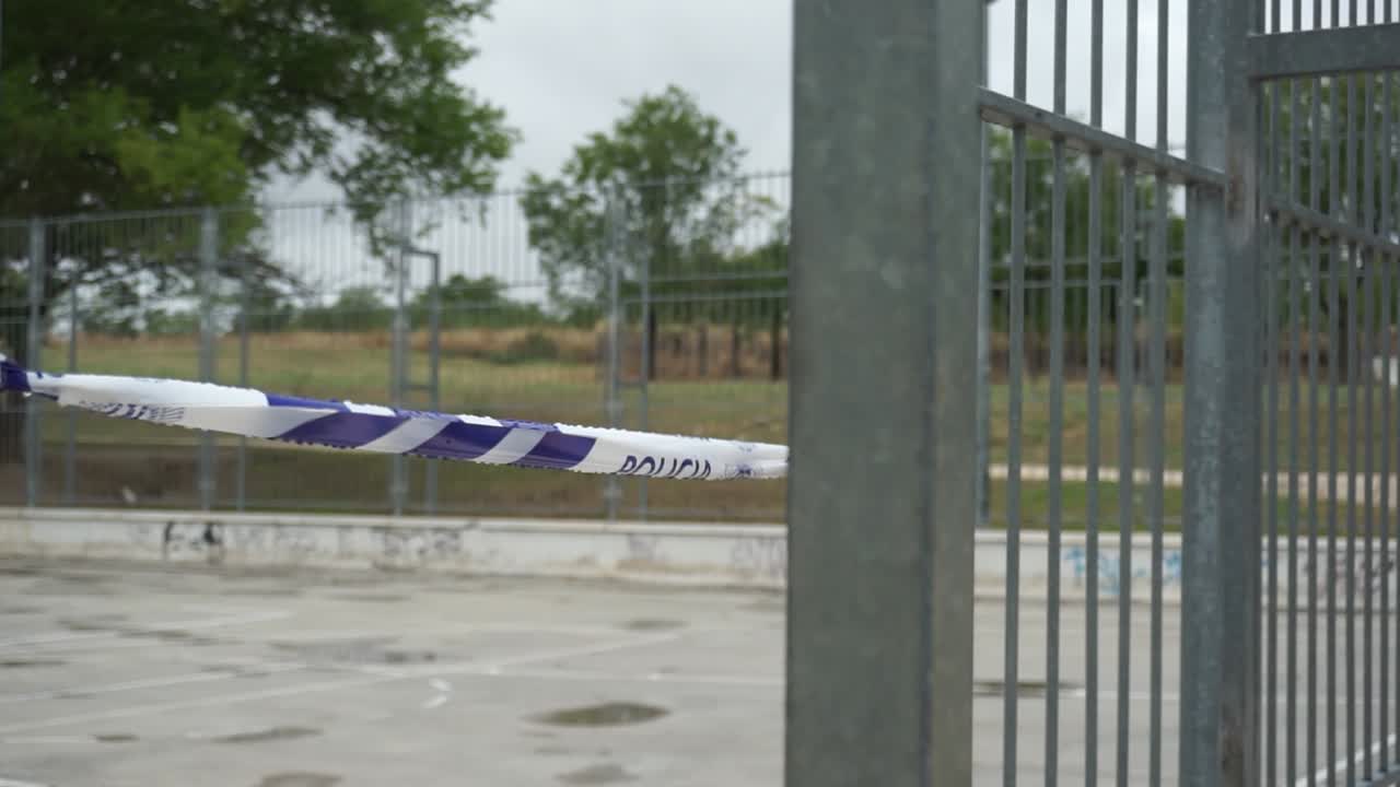 Police Tape Across a Metal Fence at a Park - Crime Scene or Restricted Area