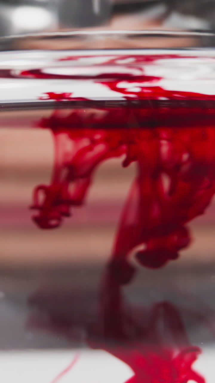 Red patterns of blood flow with diffusion in transparent liquid while scientist does test slow motion. Probe lens footage of healthcare work macro view