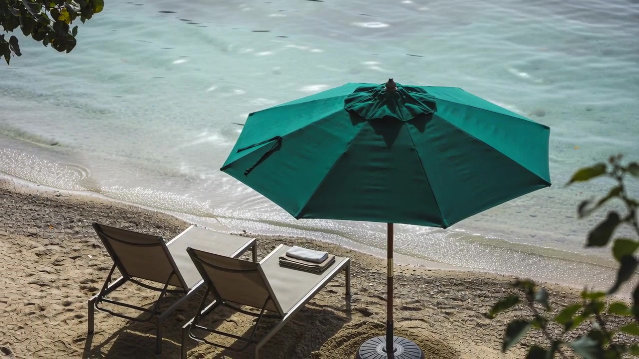 Ombrellone verde acqua ondeggiante e due lettini con asciugamano sulla riva sabbiosa, leggera brezza che sposta i riflessi.