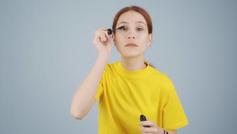 woman is applying mascara to her eyes.