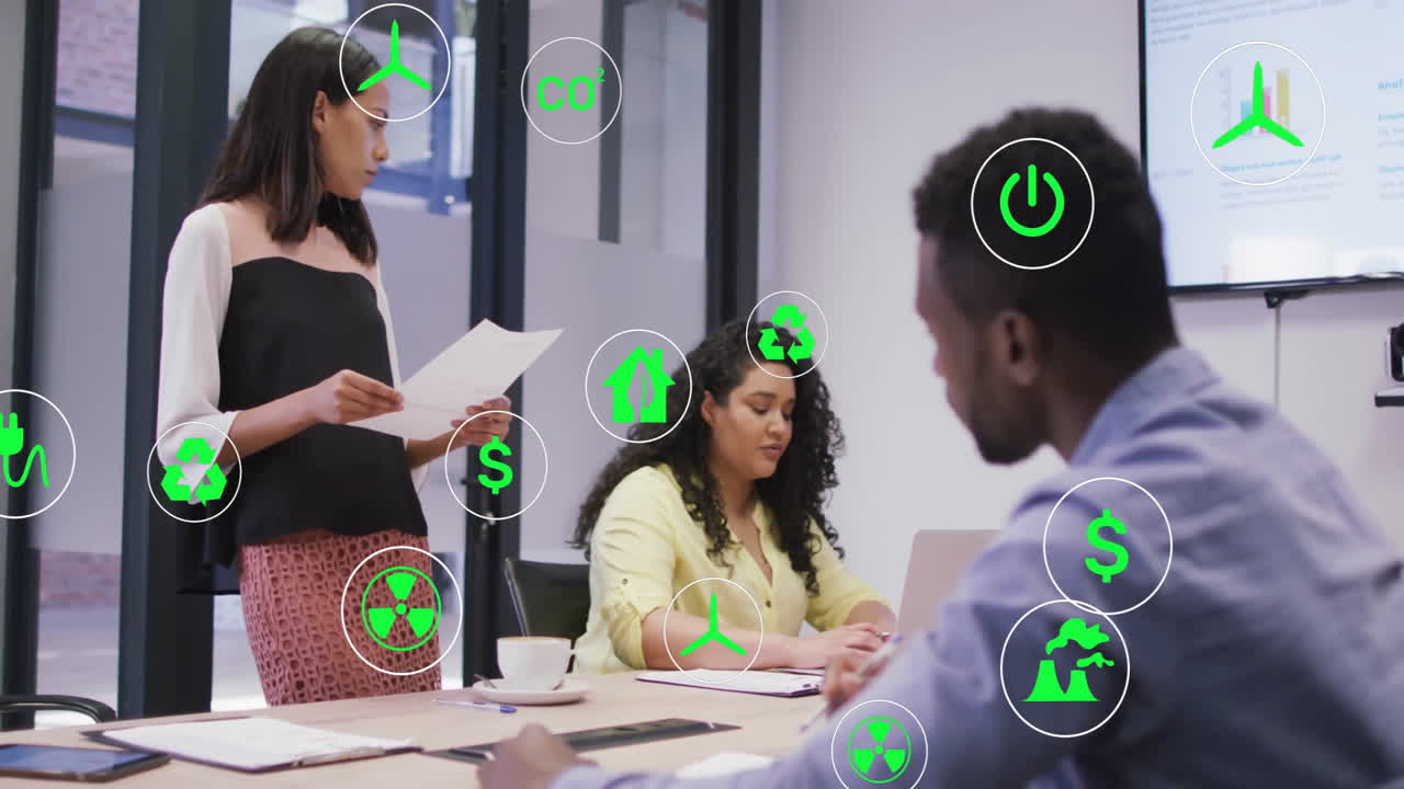 Green energy icons animation over diverse business team in meeting room