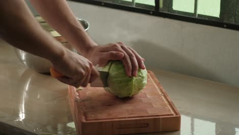 Cutting Whole Cabbage In Half On Wooden Chopping Board. - closeup shot