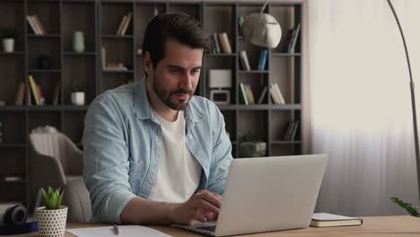 man read e-mail on laptop feels happy by good news