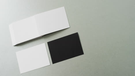 Overhead-view-of-blank-white-and-black-business-cards-on-grey-background,-copy-space,-slow-motion