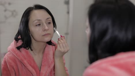 young caucasian woman applying cream mask on face. facial spa procedure at home