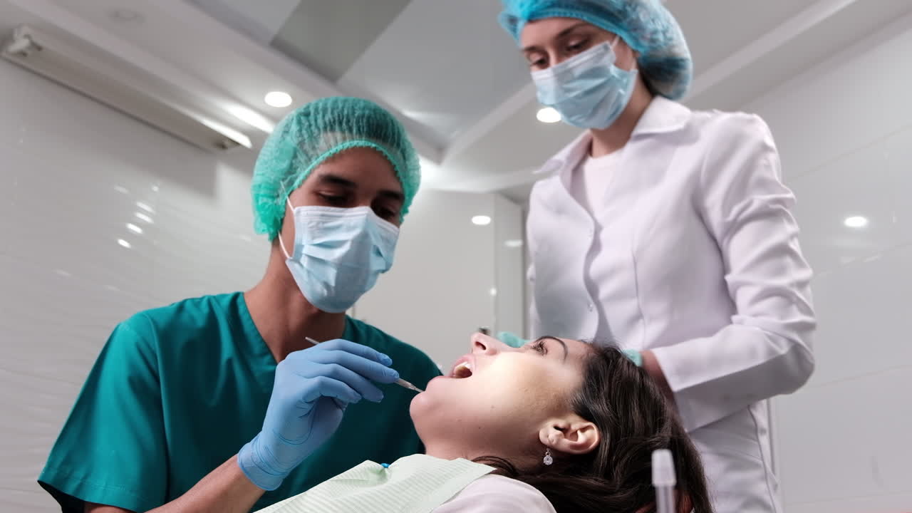 Doctor en la consulta del dentista con el paciente en la exploración, ayudado por una enfermera