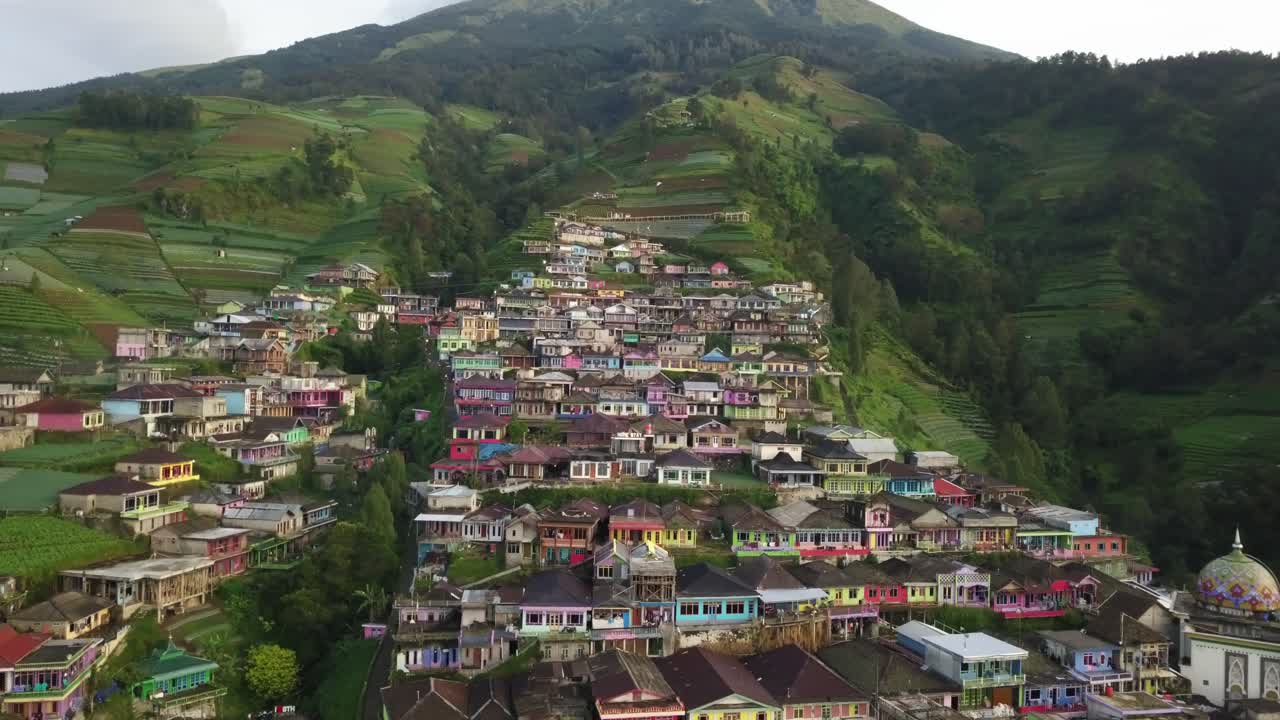 vuelo aéreo hacia atrás que muestra el colorido pueblo turístico nepal van java, magelang, indonesia - montaña verde con plantaciones que rodean la ciudad indonesia