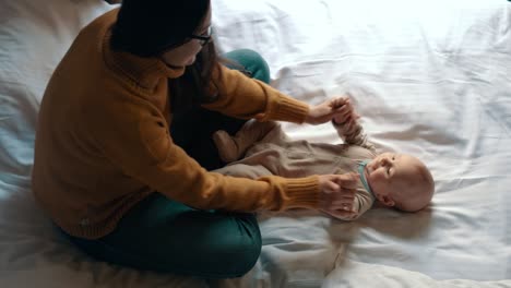 loving mother playing with baby in bed. newborn child smiling mother