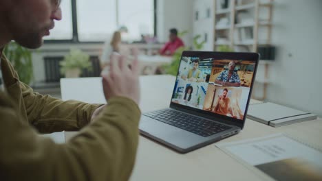 man video conferencing with business team at desk in office