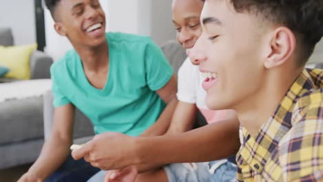 Happy-diverse-male-teenage-friends-eating-pizza-and-sitting-on-couch,-slow-motion