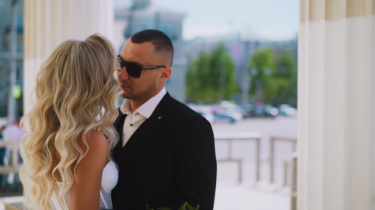hombre con gafas de sol abraza a su amada esposa con peinado por columnas