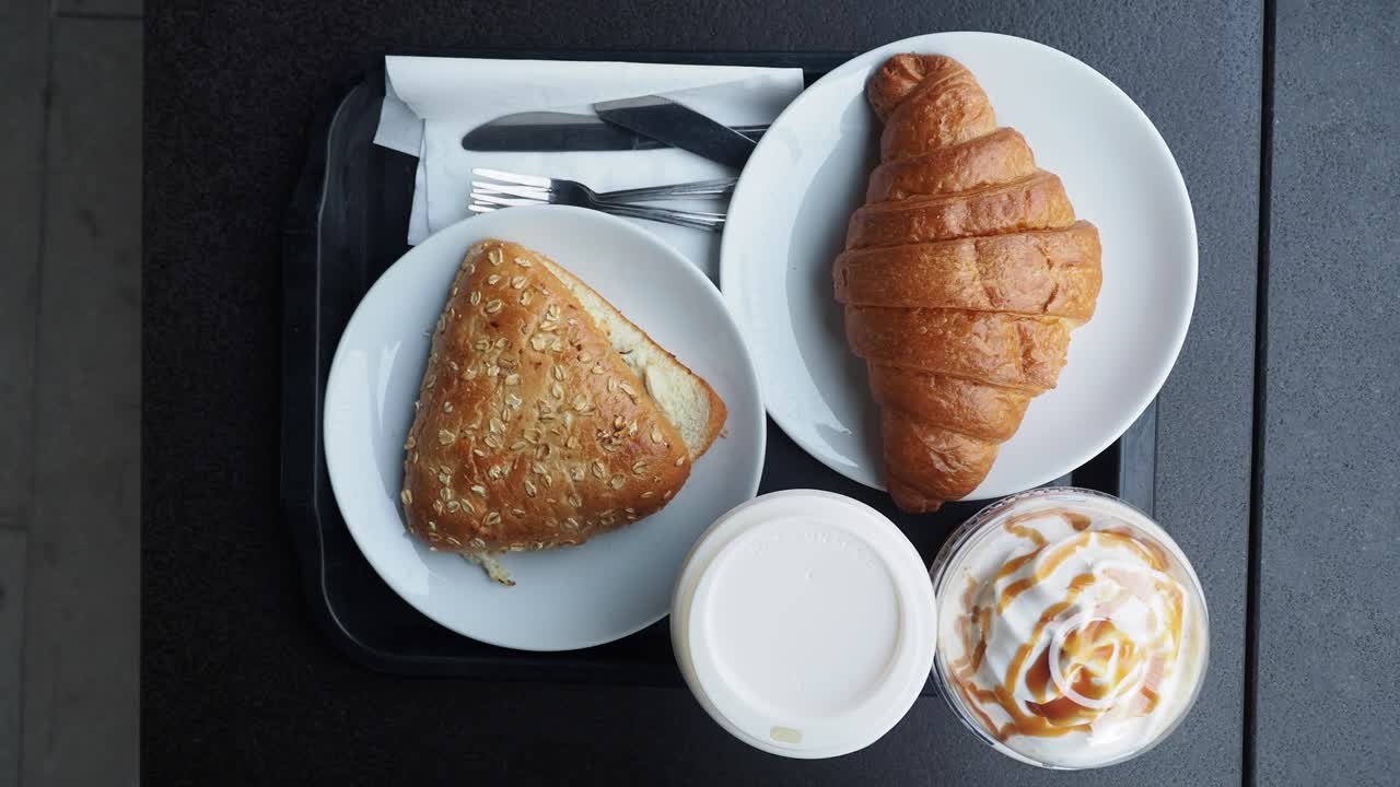 desayuno en una cafetería: croissant, sándwich y bebida de café con caramelo
