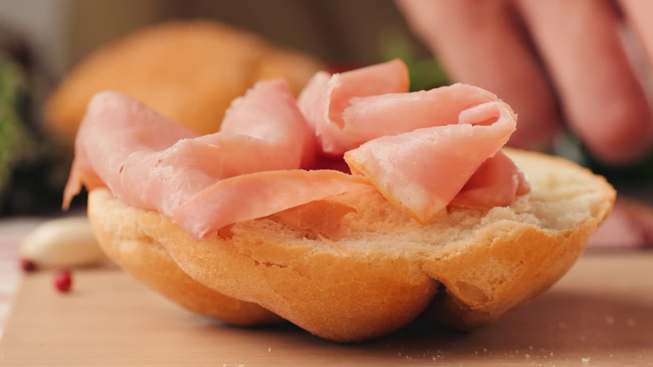 Mortadella ham sandwich, Traditional italian focaccia filled with thin pesto slices of mortadella, served by chef man in cafe restaurant. Macro of traditional italian spanish tapas antipasti.