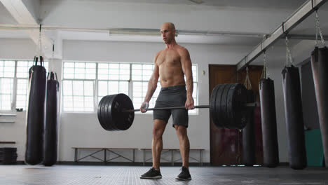 Caucasian-male-trainer-working-out-with-barbell-at-the-gym