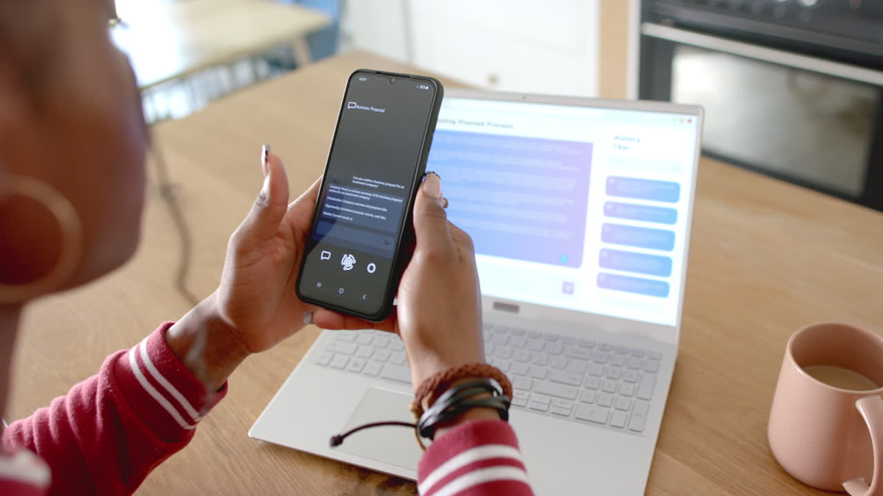 African American woman holding smartphone, showing Ai Chat Bot Screen, at home