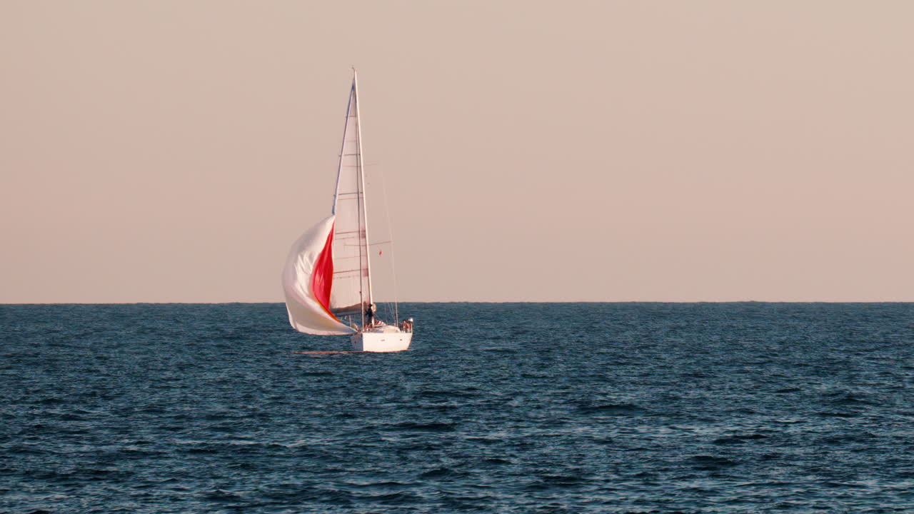 Small ship with a red sails moving on the sea in Golfe-Juan, France